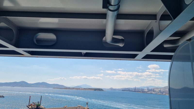View from a Virgin Voyages cruise ship balcony overlooking the sea and distant mountains against a clear blue sky.