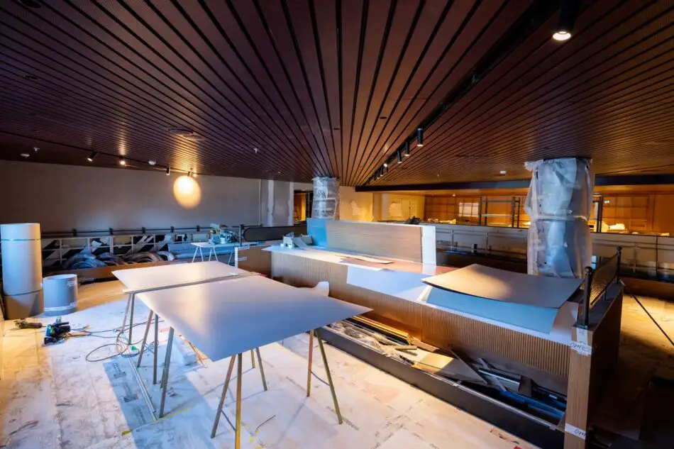 Under renovation in a spacious interior with a wood slat ceiling and work tables