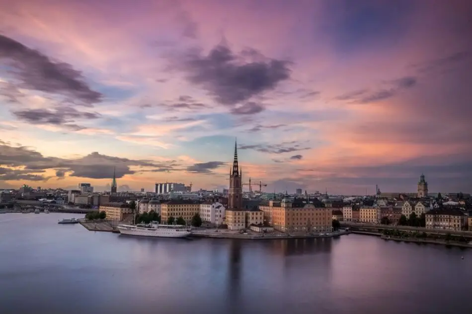 Sunset over Stockholm harbor with historic buildings and tall church spire