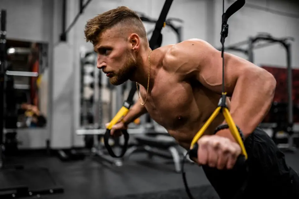 Man performs TRX suspension training in a gym