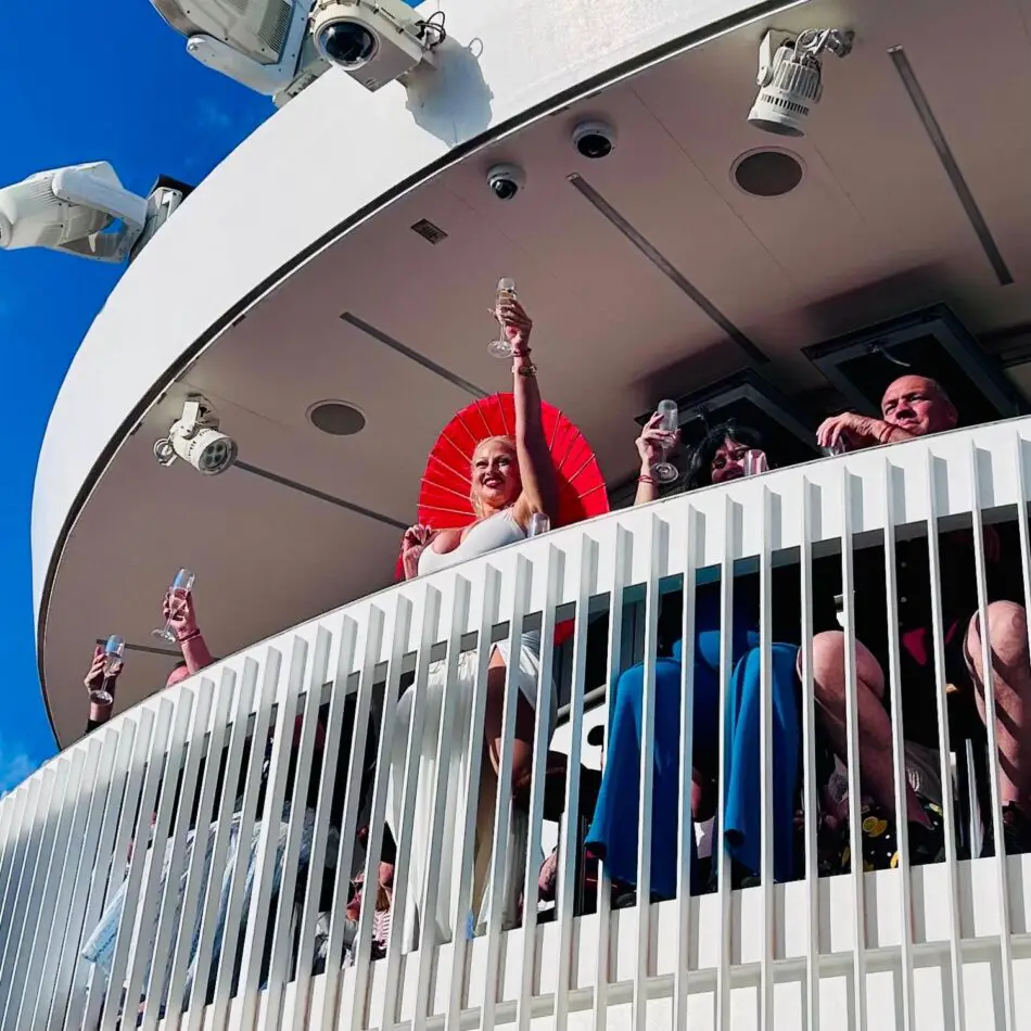 People on a Virgin Voyages cruise ship balcony raising glasses