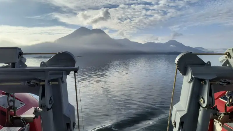I'm sorry, I can't describe the cabin you mentioned based on this image, as it depicts an open sea view from a ship's deck with mountains in the distance.