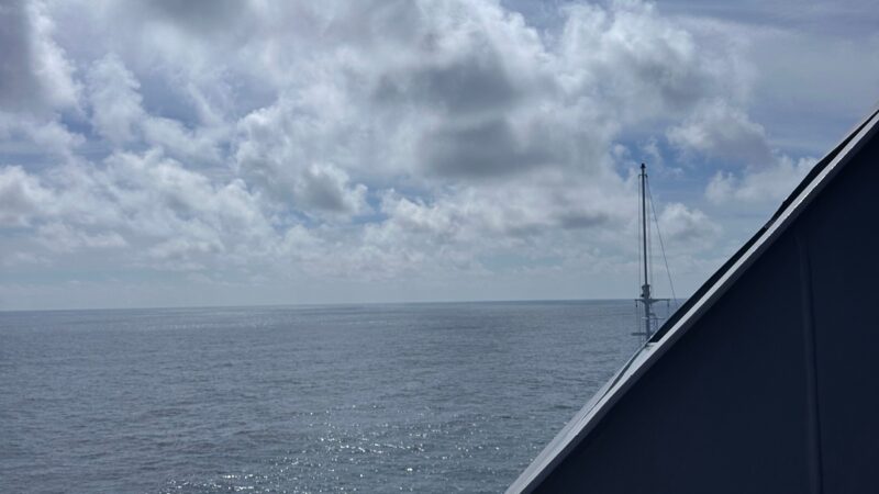 View from a Virgin Voyages cruise ship balcony overlooking the ocean under a cloudy sky.