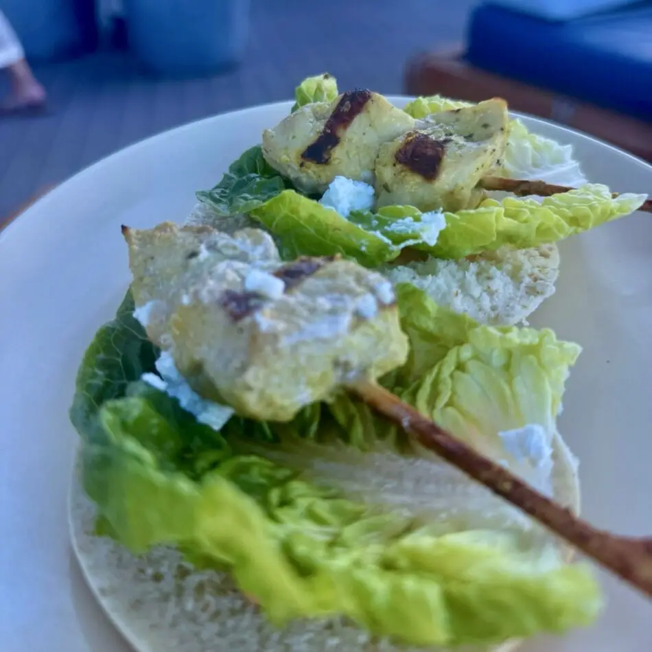 Lettuce, crusty bread, and skewered fried cubes on a plate