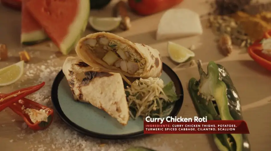 Curry Chicken Roti on a plate with lime wedges