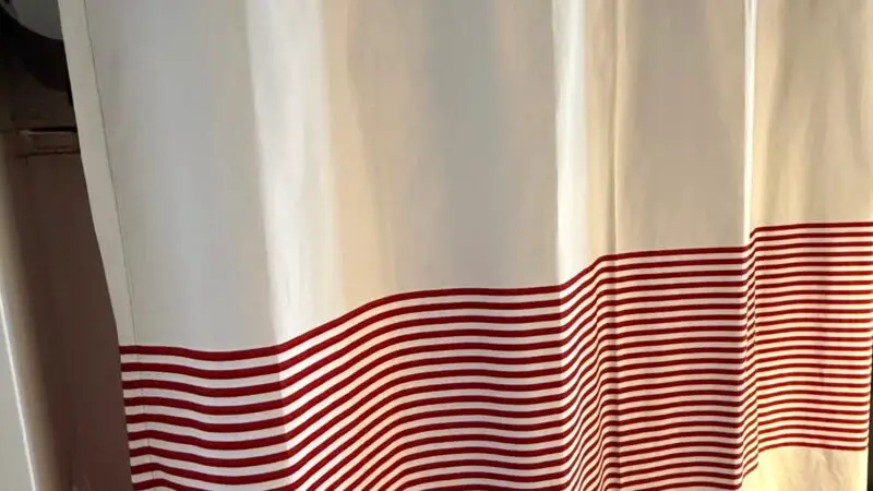 Close-up of a Virgin Voyages cruise ship cabin curtain with white and red striped design.
