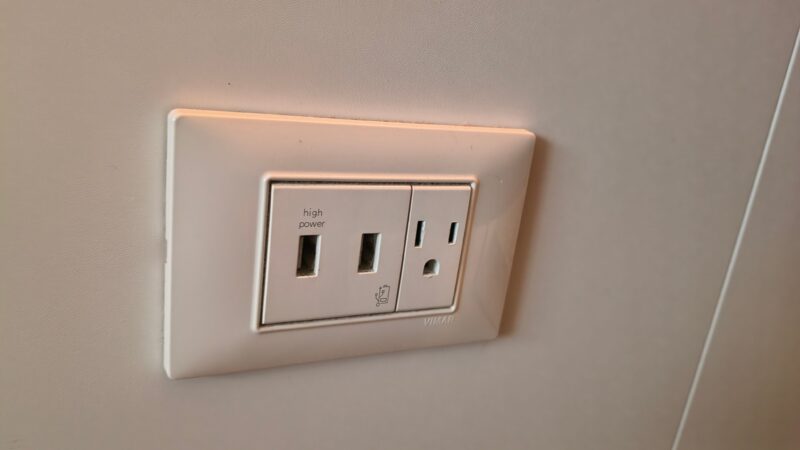 Wall outlet in a Virgin Voyages cruise ship cabin, featuring high-power and standard sockets.