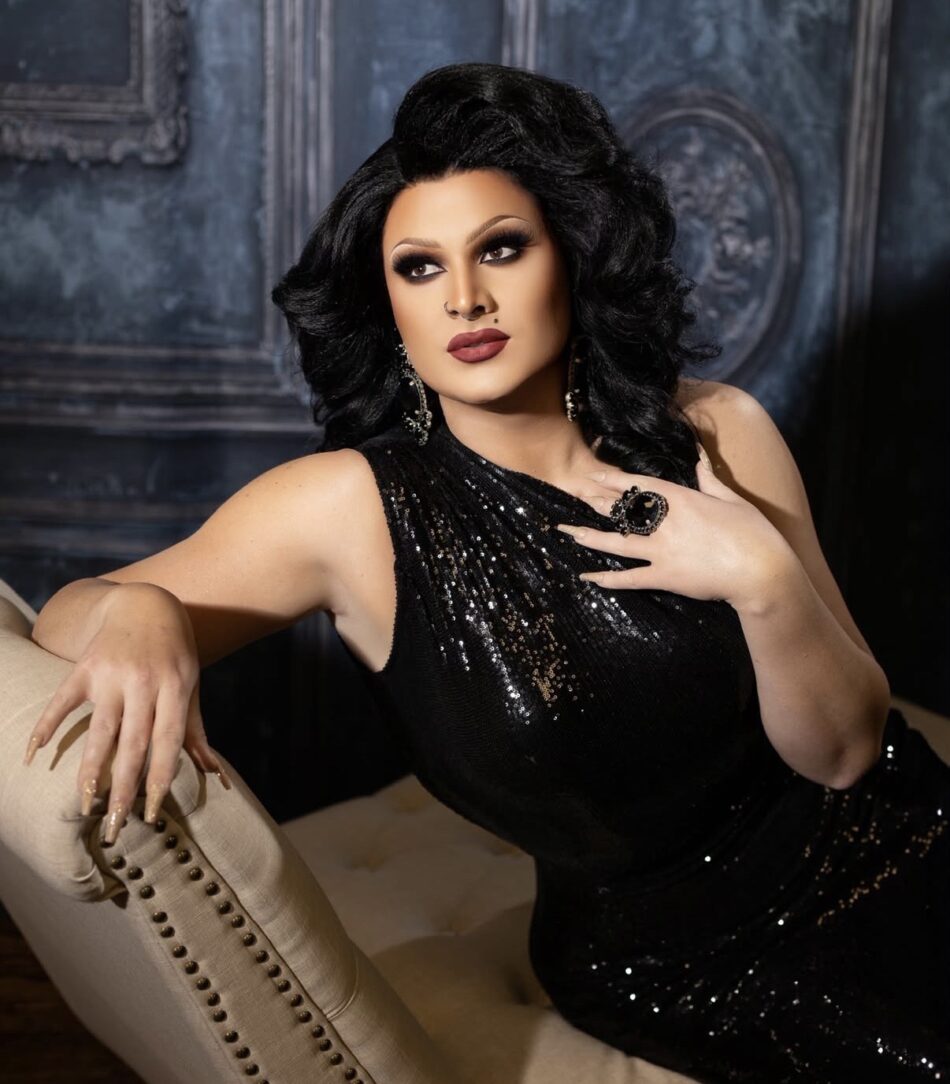 Glamorous woman in a black sequined dress posing on a beige sofa