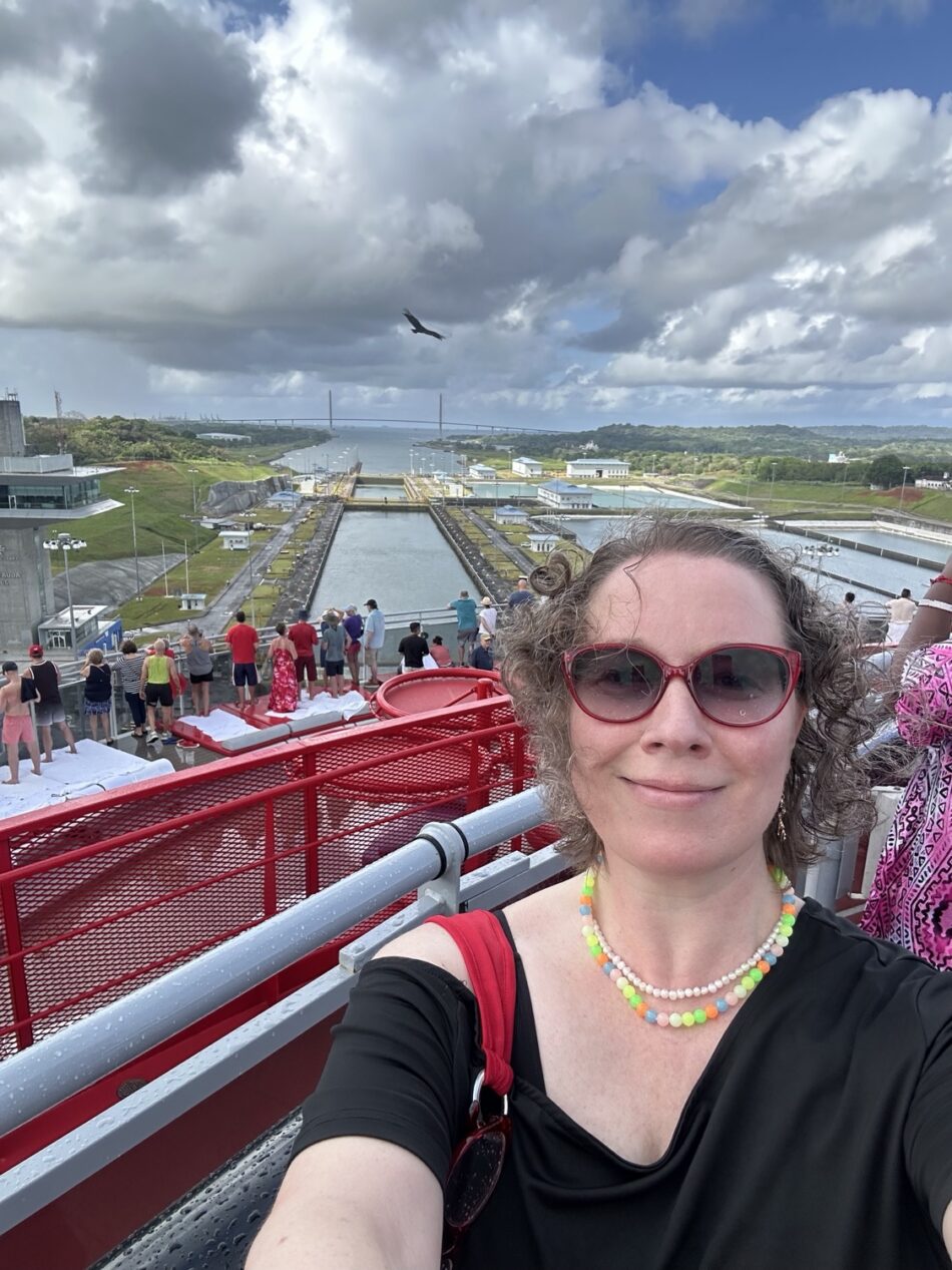 Woman taking a selfie on a Virgin Voyages cruise ship deck with passengers