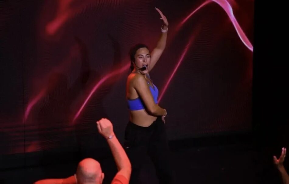 Female dancer in blue top performs on stage with headset microphone