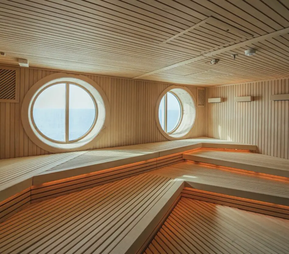 Wooden sauna interior with round porthole windows and sea view