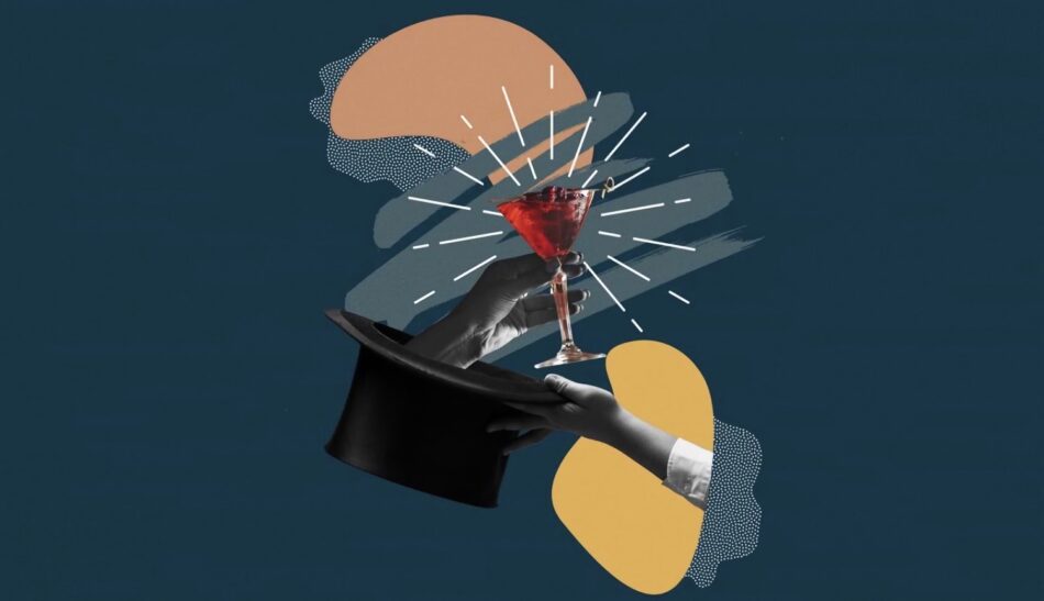 Two hands present a red cocktail in a martini glass above a magician's top hat