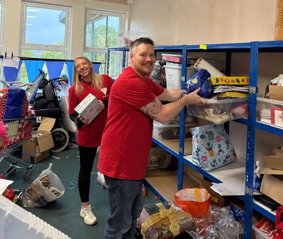 Two volunteers sorting donations on blue metal shelves in a donation center